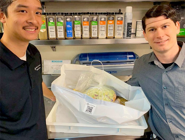 Sutter employees stand in kitchen with bags of food