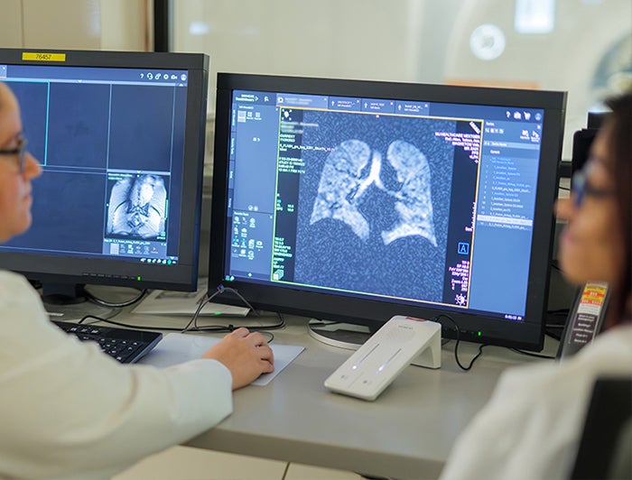 MU Health Care. clinicians sit at a desk with computer monitors displaying lung scans