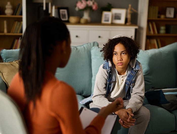 Butler Hospital. Teen sits on a sofa facing a female therapist
