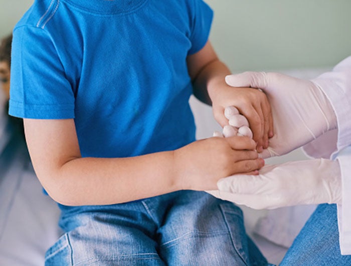 UC Davis Health Doctors Use Collarbone to Create New Upper Arm for Young Patient. A doctor in gloves holds the hands of a young patient to test the strength in the patient's arms and hands.