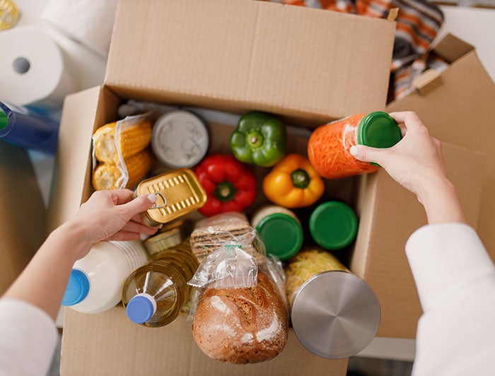 OHSU. hands reach into a cardboard box filled with groceries.