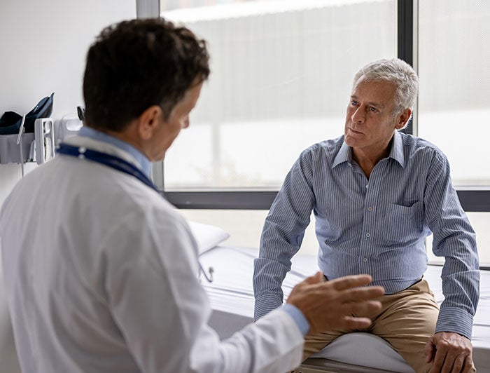 Providence Alaska. A male physician sits talking with an older male patient