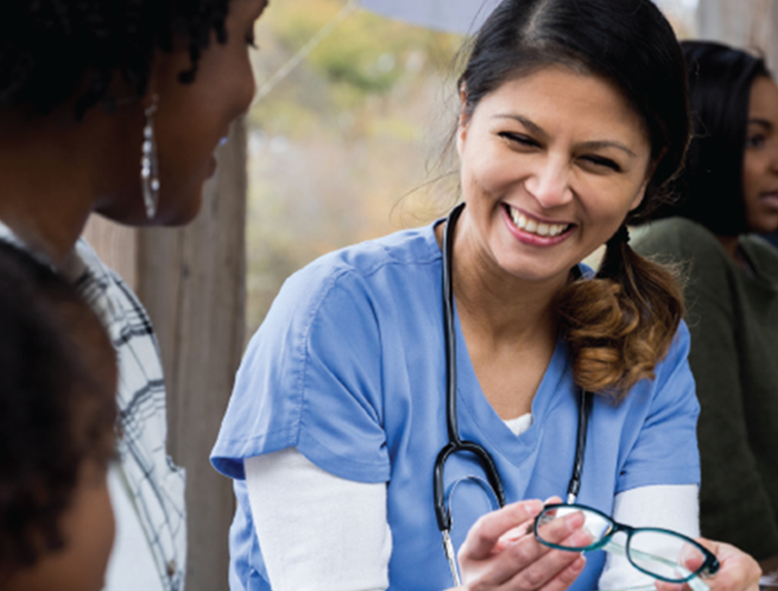 A female physician laughs with a family at a community event