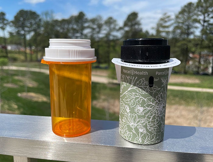 UVA Health. An orange plastic pill bottle is shown on the left, next to one of UVA's new paper pill bottles 