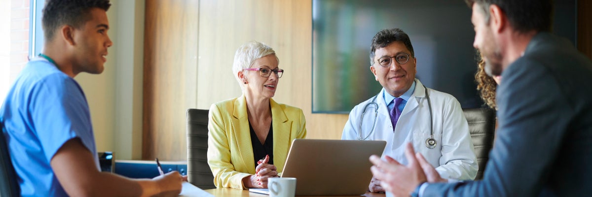 Health Professional in a meeting sitting at a table.
