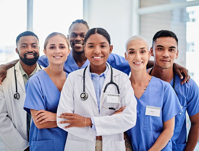 Ochsner. An ethnically diverse medical team of three men and three women wearing scrubs and white coats