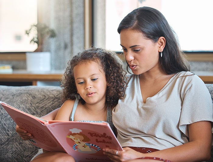 Monument Health Trash-collecting character gets kids to read. stock image of a woman and young girl reading together.
