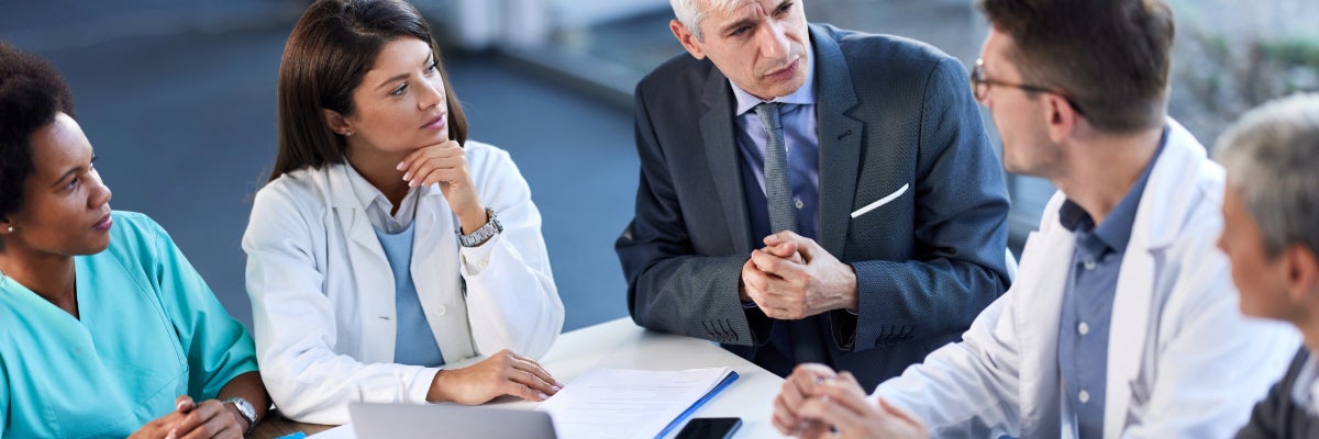 Two women, and three men at a meeting table. 