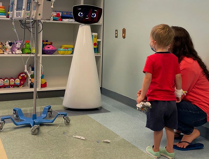 Telling the Hospital Story: UMass Memorial Medical Center – Children’s Robots, dogs and Legos help kids cope during hospital visits; Photo of patient with Robin, the interactive Robot