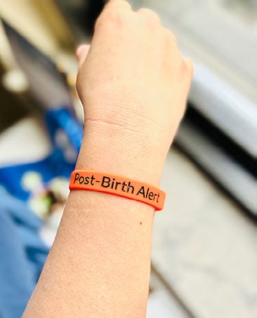 Baby with wristband with the text of Post-Birth Alert