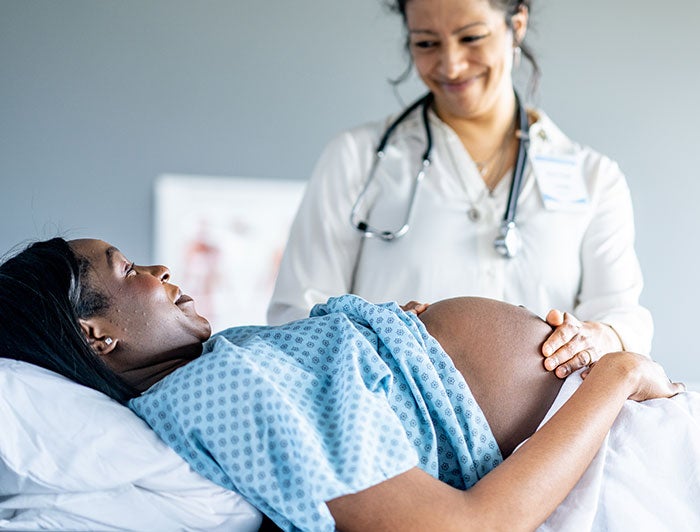 A woman sits on a sofa scanning her continuous glucose monitor with her phone