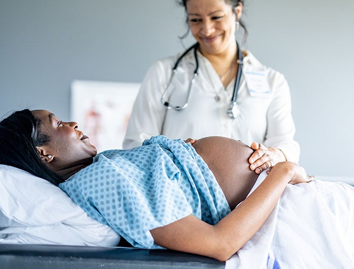 A pregnant mother and health worker talk in a hospital room