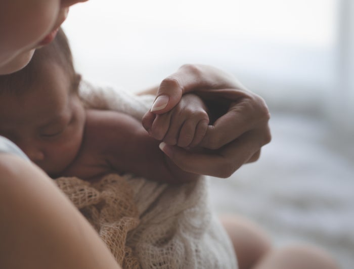 A mother holds a swaddled baby