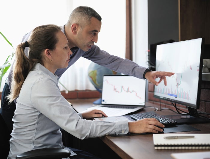 A man and woman review a chart on a computer screen