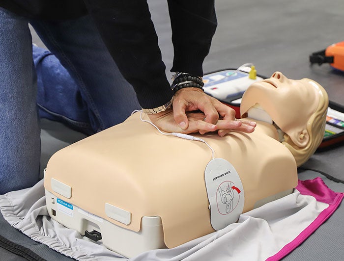 person practices chest compressions on a CPR dummy