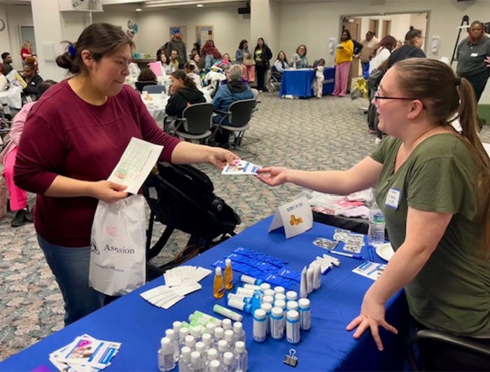 An Ascension employee gives supplies to a community baby shower attendee