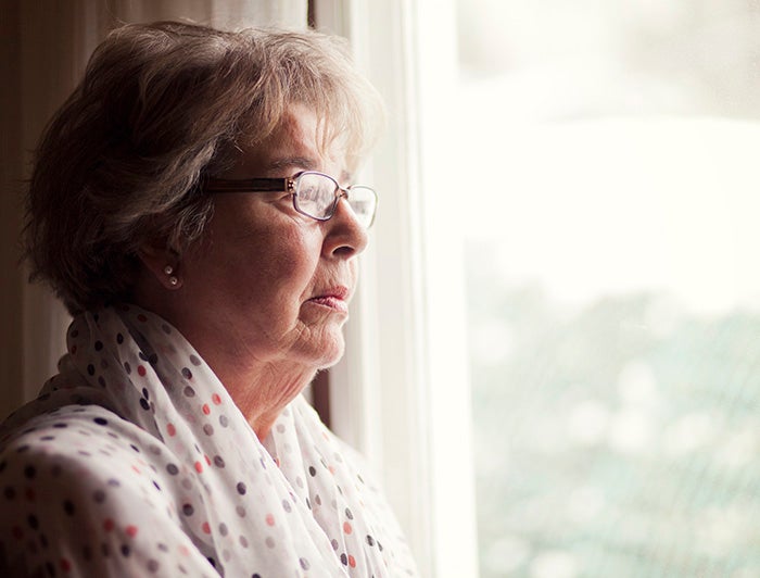 An older woman staring out a window
