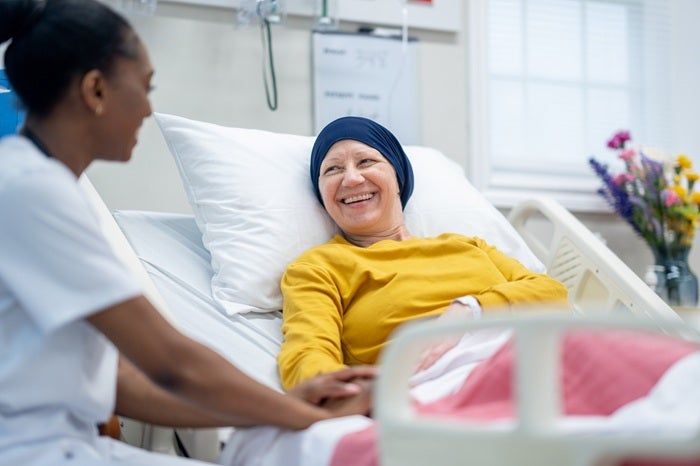 A woman in hospital bed talking with a health worker