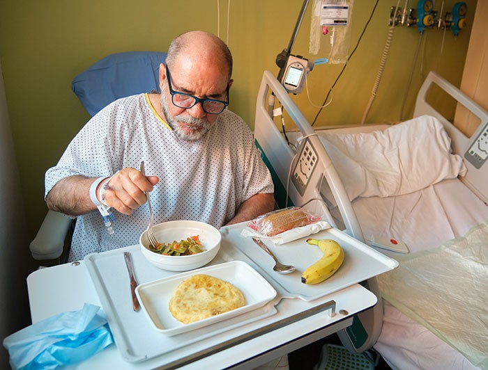 a patient sits next to his hospital bed eating
