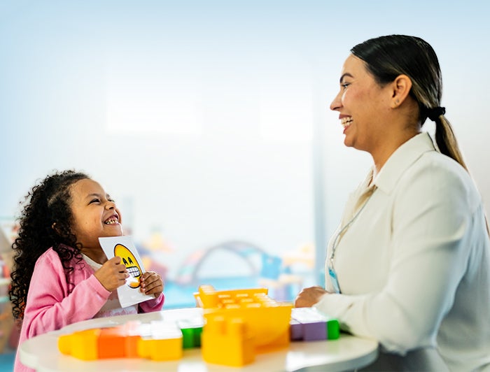 female therapist sits with child using emotion flashcards