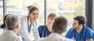 National Rural Health Day Workforce Image -- A woman doctor standing up leading a meeting of a medical team seated around a table.
