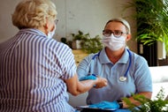 A clinician takes a patient's pulse in a hospital-at-home setting.