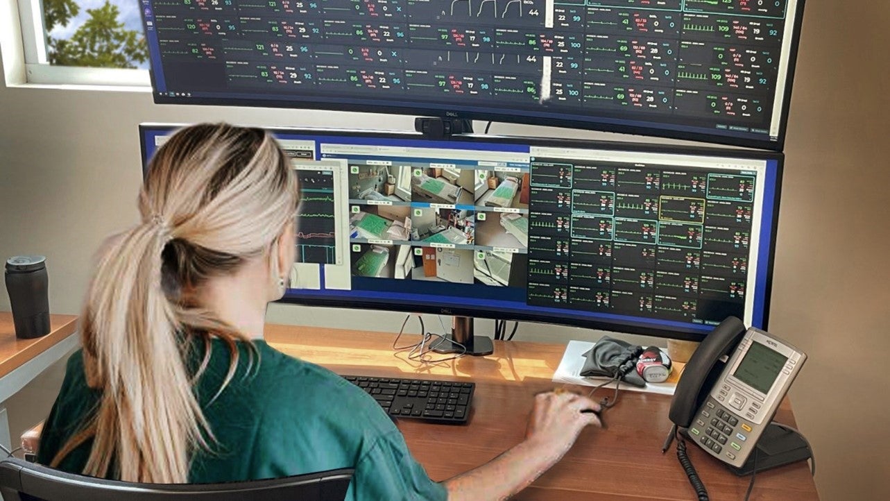 Guthrie Clinic Adds Virtual Care Hub to Address Nursing Shortage, Boost Patient Access and Safety. A clinician sits at a desk working on a computer with a virtual care hub software platform displayed on the screen in front of her.