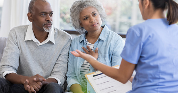 How to Improve Shared Decision-Making and Informed Consent. A clinician in scrubs talks to an older Black couple.