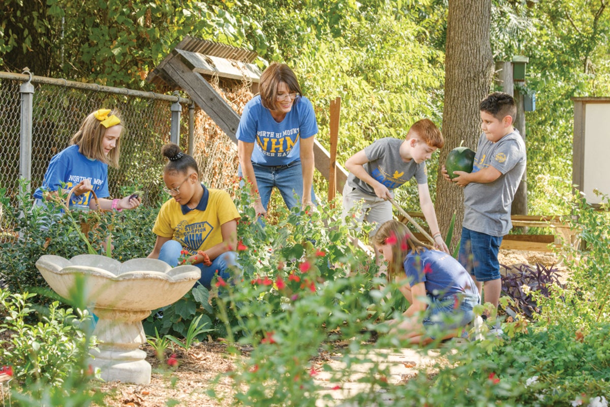 NHM garden. A women works with children in a garden.