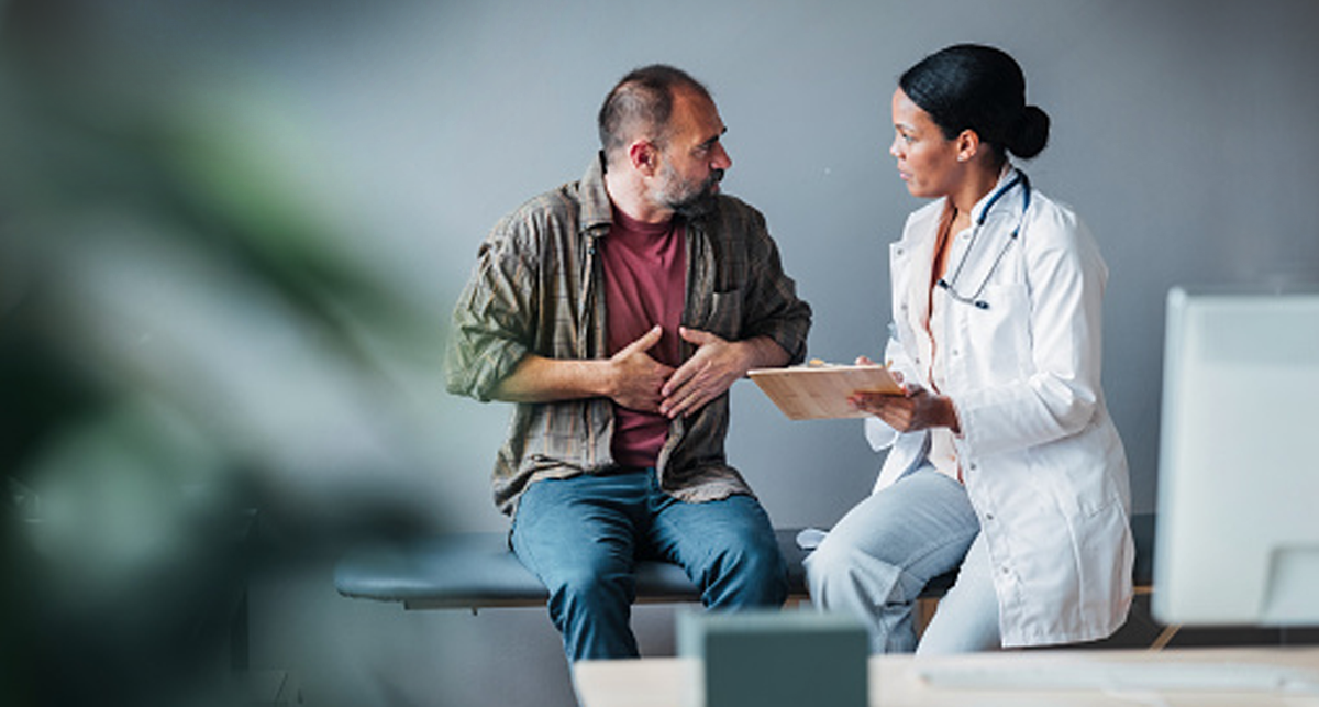 Study Finds Bed-Free Care Pathway Improves ED Flow. A patient in an emergency room explain stomach pain he is experiencing to a nurse who is documenting his symptoms.