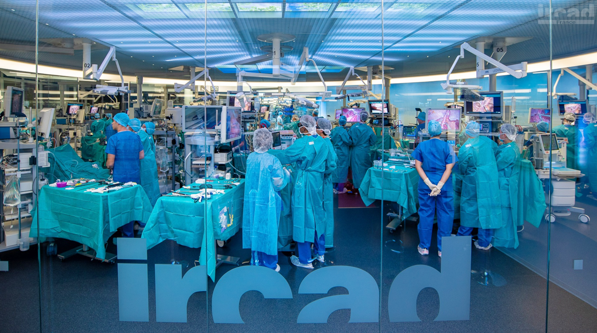 Surgeons, Medtech Companies and Startups Join Forces to Drive Innovation. Surgeons and nurses in an operating room with the IRCAD logo on the glass wall of the room.