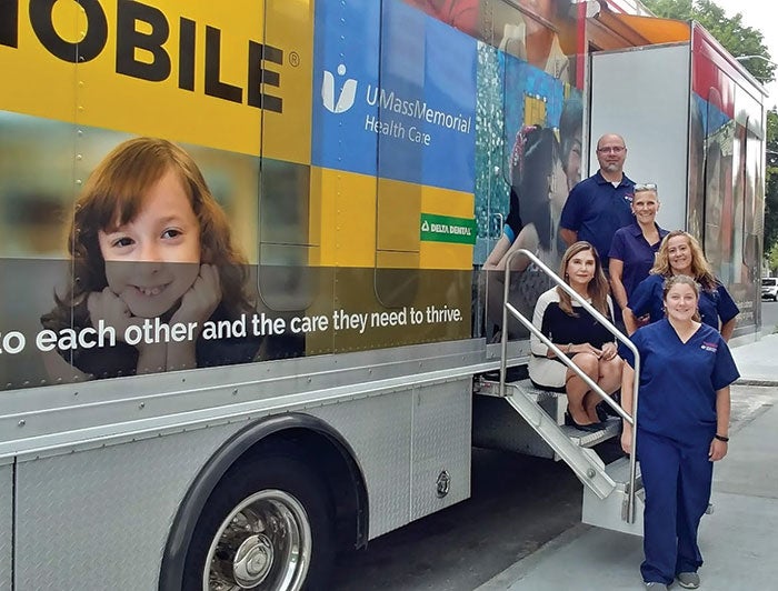 UMass Memorial Prioritizes ‘Anchor Mission’ Work in Its Community. Clinicians from UMass Memorial stand on the steps of their mobile medical and dental clinic.