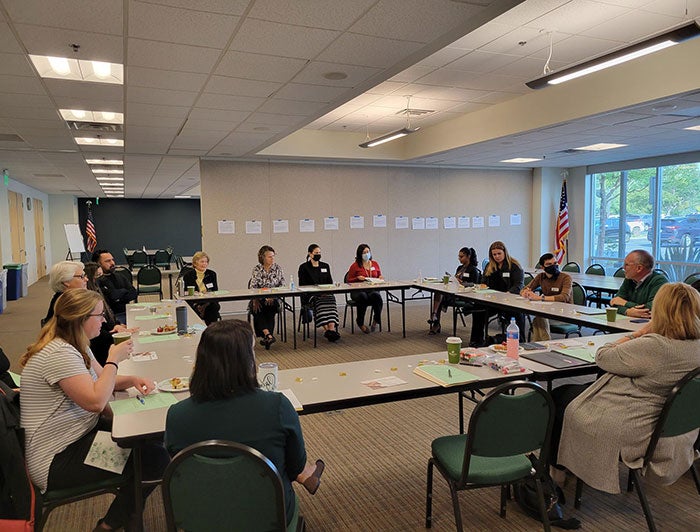 Community Memorial Health System. People around tables arranged in a square at a caregiver navigator program meeting.