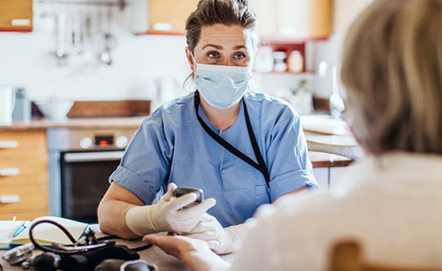 Hospital-at-Home Gains Momentum with Added Flexibilities, New Entrants. A clinician wearing a masks evaluates a patient.