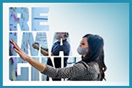 Disrupting Behavioral Health: Achieving Greater Access and Equity. Reimagine. Two people wearing masks putting Post-It Notes on a whiteboard.