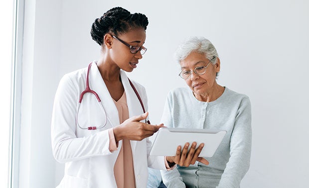 Hospitals Make Progress on Value-Based Payment Models. A young woman clinician going over a chart with an elderly woman.