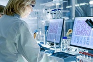 AI Image Recognition Moves from Radiology to Pathology. Clinician working with lab equipment while looking at medical imaging on a screen.