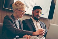 Set Your Strategy with Help from AHA Annual Survey Database. A female and male coworker review AHA Annual Survey Database data on a computer screen.