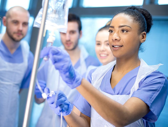 MaineHealth. A clinician adjusts an IV while other clinicians look on.