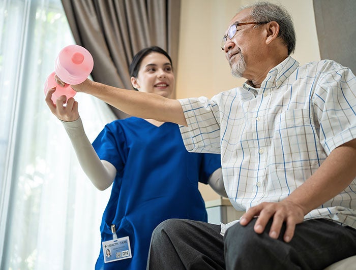 Cheyenne Regional Medical Center. Photo of a female nurse in scrubs helping an older man exercise his arms