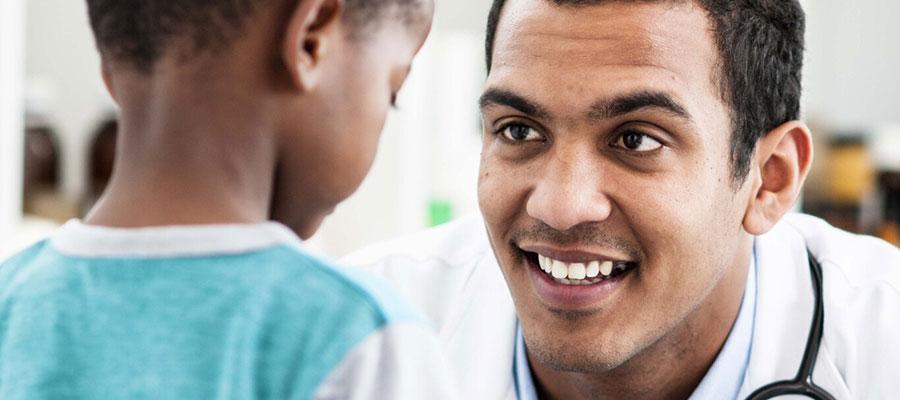 Image of physician crouching down and smiling at young patient