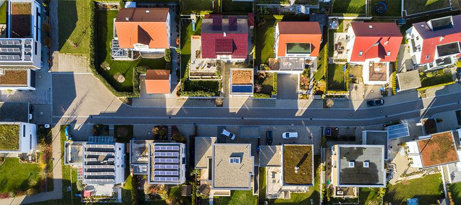 To Advance Health Equity, You Must Invest in Communities. An overhead photo of a street in a neighborhood with large, two-story houses on both sides of the street.