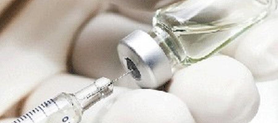 A clinicians gloved hand draws a syringe of vaccine from a vial.