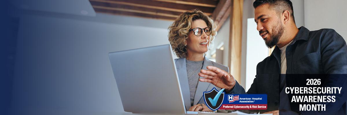 2026 Cybersecurity Awareness Month. A woman and a man in front of a desktop reviewing cybersecurity settings.