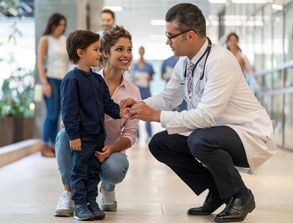 Stock image of a doctor crouching to speak with a little boy 