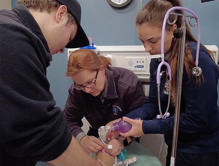 Three health workers, two female and one male, work through a simulation