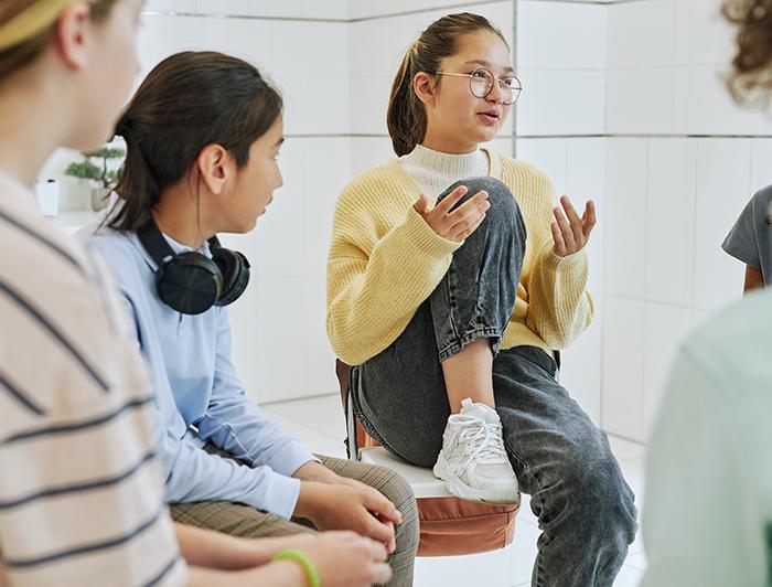 Teen girls sit in a circle talking