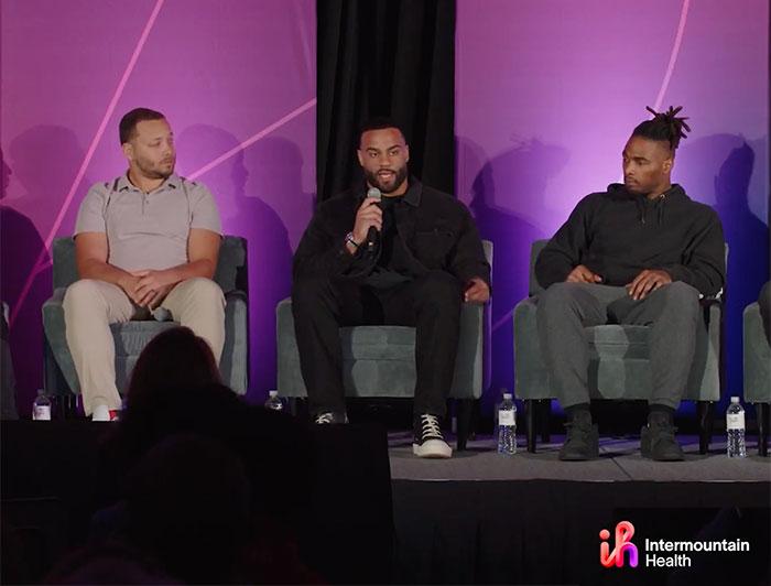 Three young black men sit on a stage talking during a panel