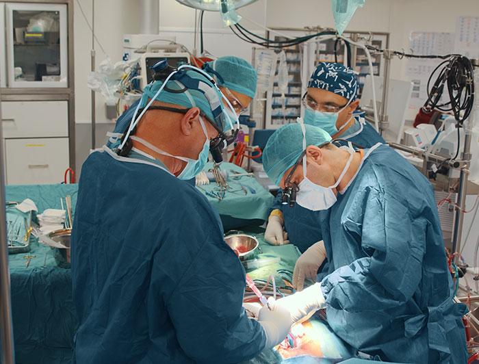 Four surgeons operate on a patient in surgery