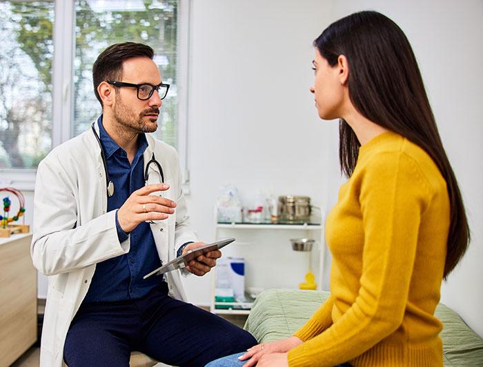 A woman sits in consultation with a male health worker 